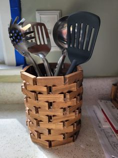 a wooden basket with utensils in it