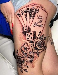 a woman's thigh with playing cards and roses on it