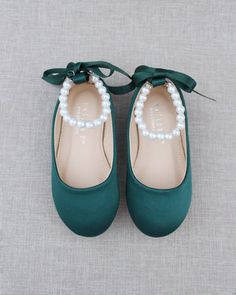 a pair of green shoes with pearls on them