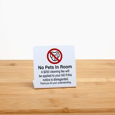 a sign on a wooden table warning people not to pets in the room or no cats in the room