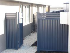 two metal gates are open in front of a house that has gravel on the ground