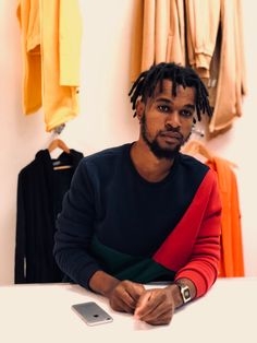 a man with dreadlocks sitting at a table in front of a cell phone