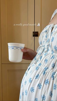 a pregnant woman holding a cup in her hand