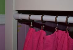 two pink towels hanging from the side of a white rail in front of a green wall