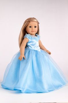 a doll with blonde hair wearing a blue dress on a white background, looking at the camera