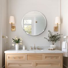 a bathroom vanity with two sinks and a round mirror on the wall above it,