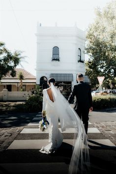 a bride and groom walking across the street