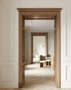 an open door leading to a living room with white walls and parquet flooring