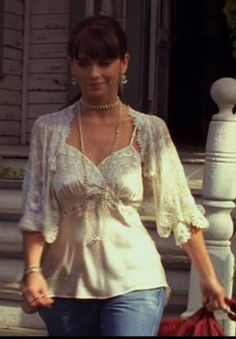 a woman is walking down the steps with a handbag in her other hand and wearing a white blouse