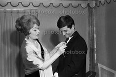 an old black and white photo of a man helping a woman put on her tie