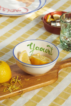 two bowls filled with lemons on top of a wooden cutting board next to glasses