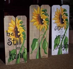 three sunflowers painted on wooden boards with the words, be still and joy