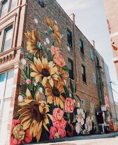 a large mural painted on the side of a brick building with sunflowers and other flowers