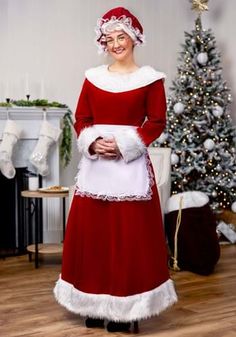 a woman dressed as santa clause standing in front of a christmas tree