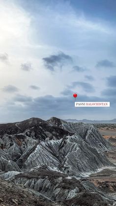 the mountains are covered in snow and there is a red balloon flying over them on top