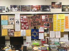 a bulletin board covered in posters and pictures next to a computer desk with a keyboard on it