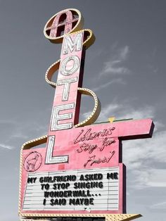 a large neon sign that is on the side of a building in front of a cloudy sky