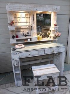 an old desk with a mirror and lights on it in front of a house that is painted white