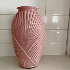 a pink vase sitting on top of a counter next to a white tile backsplash