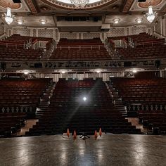 an empty auditorium with lights on the ceiling and no people in seats at the stage