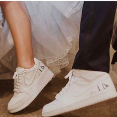 two people standing next to each other wearing white shoes