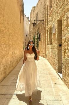 a woman in white dress walking down an alley way