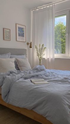 a bed with blue sheets and pillows in a bedroom next to a large window on the wall