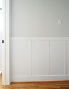 an empty room with white paneling and wood flooring on the side of the wall