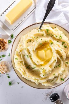 mashed potatoes with butter and parsley in a bowl on a white tablecloth