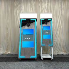 two large machines sitting next to each other on top of a carpeted floor in front of a curtain