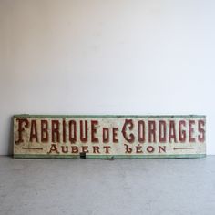 an old fashioned sign is displayed on the wall in front of a plain white wall