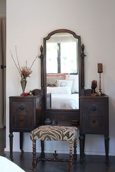 a bedroom with a zebra print foot stool and dresser in front of a large mirror