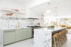 a large kitchen with marble counter tops and green cabinets, along with bar stools