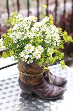 a pair of boots with flowers in them sitting on a table