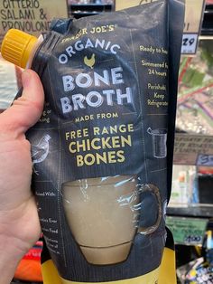 a hand holding a bag of bone broth made from free range chicken bones in a store