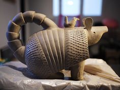 an animal statue sitting on top of a table next to a piece of cardboard paper