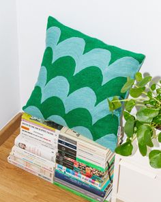 a stack of books sitting on top of a wooden floor next to a green pillow