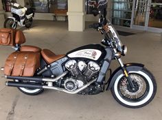 a motorcycle parked in front of a building with brown leather seat covers on it's back