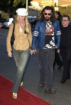 a man and woman walking down the red carpet in front of some other people on a city street