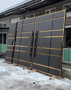 two large black and gold doors are in front of a building with snow on the ground