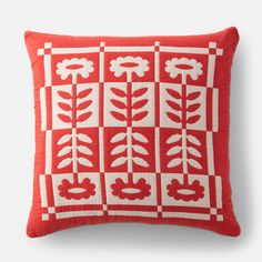 a red and white pillow with flowers on the front, in an embroidered pattern that has been