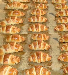 freshly baked croissants are lined up on a baking sheet and ready to go into the oven