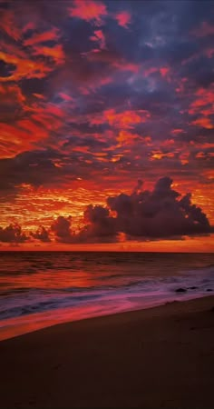 the sun is setting over the ocean with clouds in the sky and on the beach