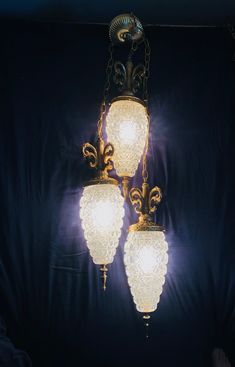 three light fixtures hanging from a ceiling in a room with black walls and blue curtains