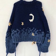 a blue sweater with gold stars on it and a crescent in the middle, hanging from a hook