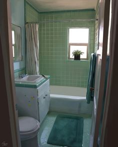 a bathroom with green tile and white fixtures