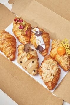 there are many croissants with different toppings on them in the box