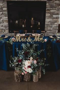 the table is set up with blue linens and floral centerpieces, along with wooden logs