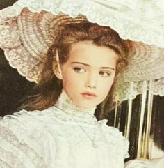 an old photo of a woman wearing a white dress and hat