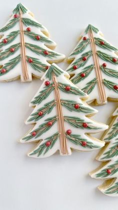 three decorated christmas tree cookies on a white surface